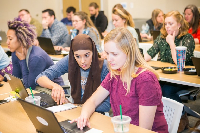 Photo of two women working over a computer.